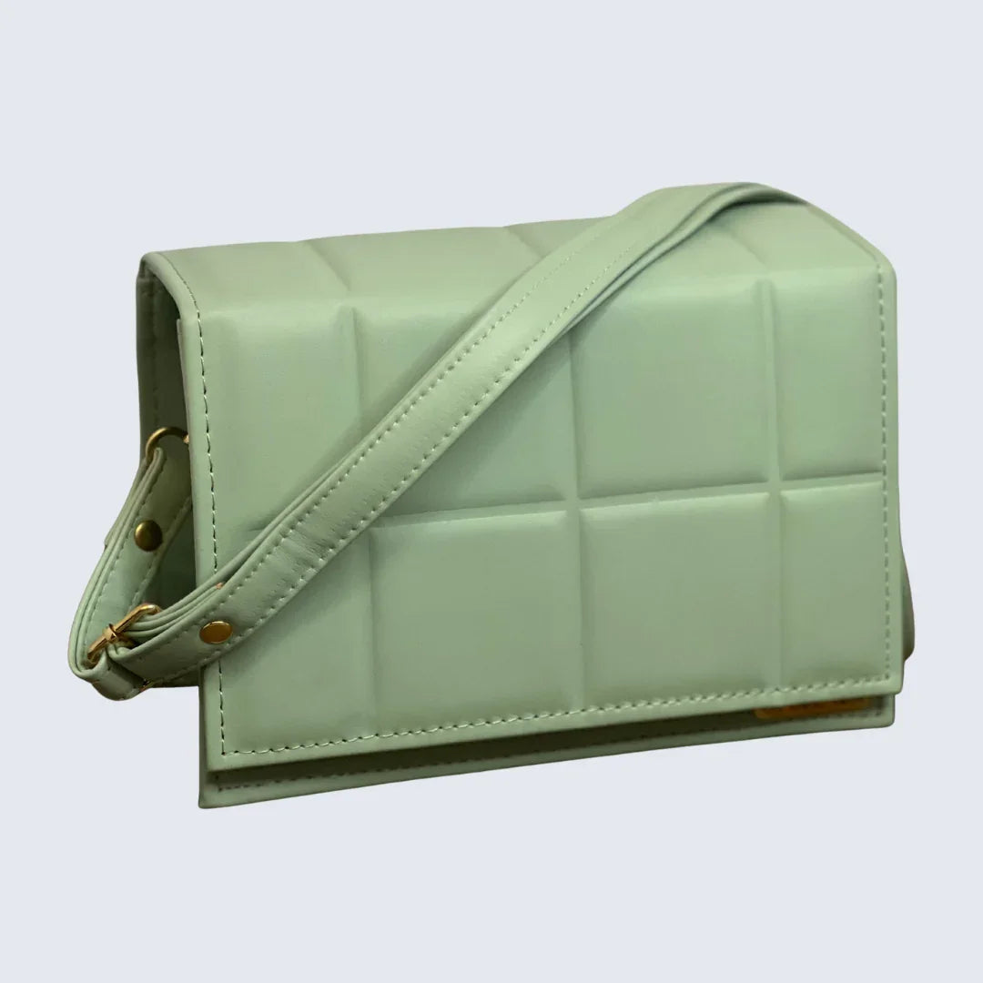 Light green quilted handbag with a strap on a light gray background