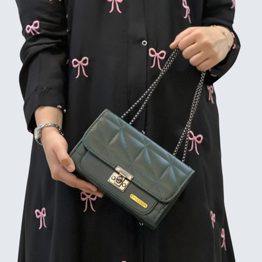 Person holding a green quilted handbag with a black dress featuring pink bows in the background