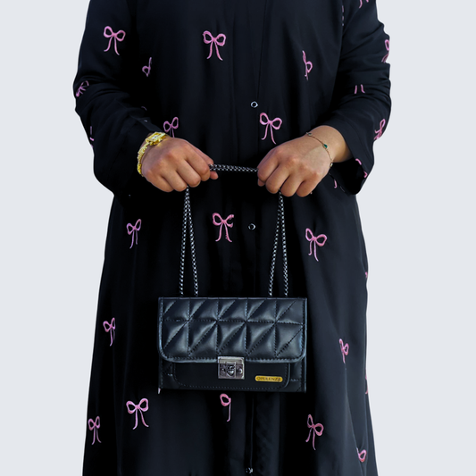 Person holding a black quilted handbag with a white background