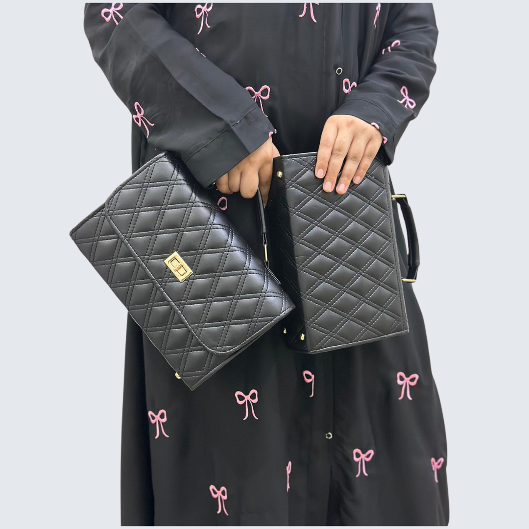 Person holding two black quilted handbags with a light gray background