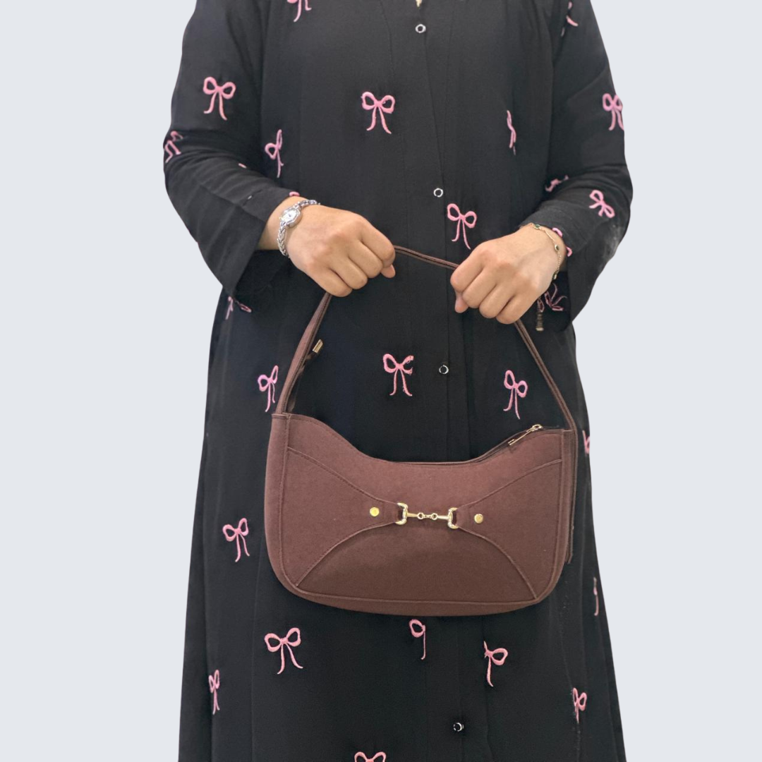 Person holding a brown handbag against a plain background