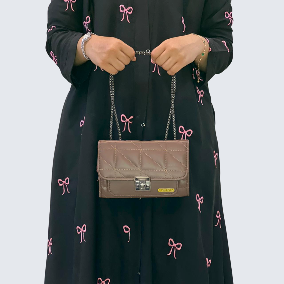 Person holding a brown handbag with a plain background